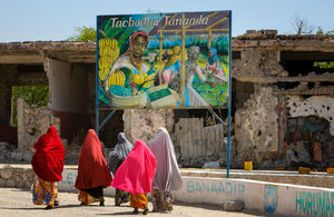 Somali woman walk past a billboard mural.  AU-UN IST PHOTO / STUART PRICE