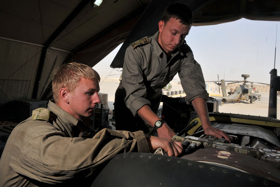 Aircraft technicians service an Apache helicopter