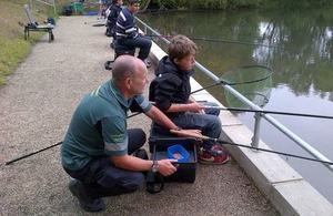 An Environment Agency officer helping a child fish