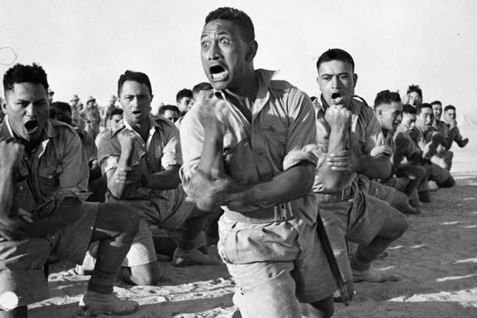 Maori troops perform the traditional 'Haka' during an inspection of the Auckland Infantry Battalion by King George of Greece, July 1941.